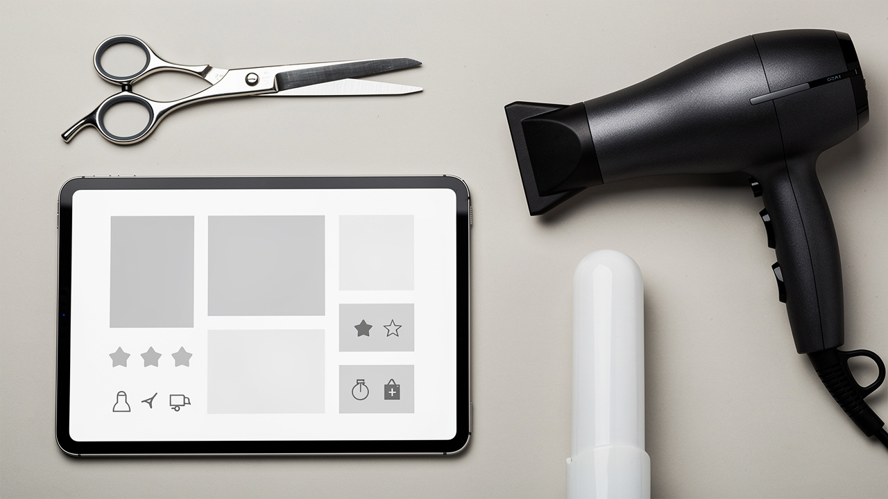 Gros plan réaliste sur du matériel de coiffure professionnel disposé à côté d’une tablette présentant une interface produit visuelle sans contenu lisible.